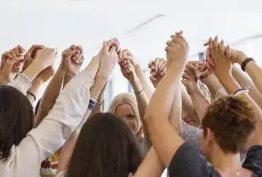 students raise their hands and holding each other